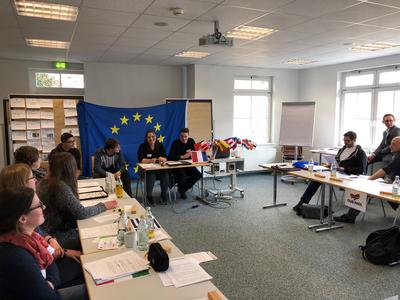 Bild vergrößern: Die Auszubildenden bei der Vorstellung ihrer selbst erarbeiteten Richtlinie für eine gemeinsame EU-Asylpolitik im Rahmen einer fiktiven Pressekonferenz.