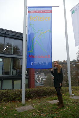 Bild vergr&ouml;&szlig;ern: Die Gleichstellungsbeauftrage des Landkreises Calw, Sarah Tonhauser, mit der gehissten Flagge von Terre des Femmes vor dem Landratsamt Calw.